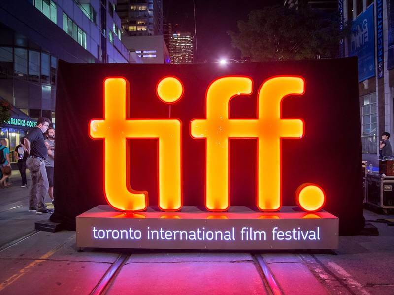 A photo in an urban area with the words "TIFF: Toronto International Film Festival" lit up against a black backdrop