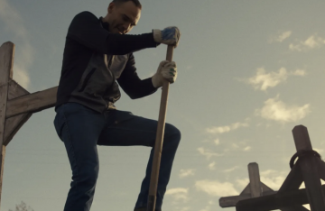 A white man digging in a cemetery with a shovel