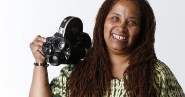 Headshot of Zeinabu irene Davis holding a camera and smiling